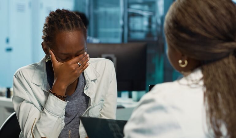 Female physician and patient examining health care reports focusing on cancer diagnosis, radiation therapy and wellbeing strategies to combat illness in a professional clinic setting. Camera A.