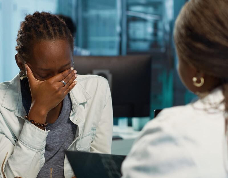 Female physician and patient examining health care reports focusing on cancer diagnosis, radiation therapy and wellbeing strategies to combat illness in a professional clinic setting. Camera A.
